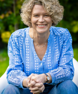 Je ne sais pas qui est la personne.
Femme souriante en chemise bleue dans jardin